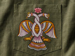 Load image into Gallery viewer, Close-up of hand-painted Odisha Pattachitra detailing on a linen shirt pocket showing intertwined bird forms, lotus elements, and fine painted linework.