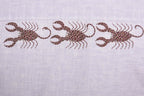 Close-up of three hand-painted Bhil scorpion artworks across back shoulder panel on linen shirt showing detailed dot work.