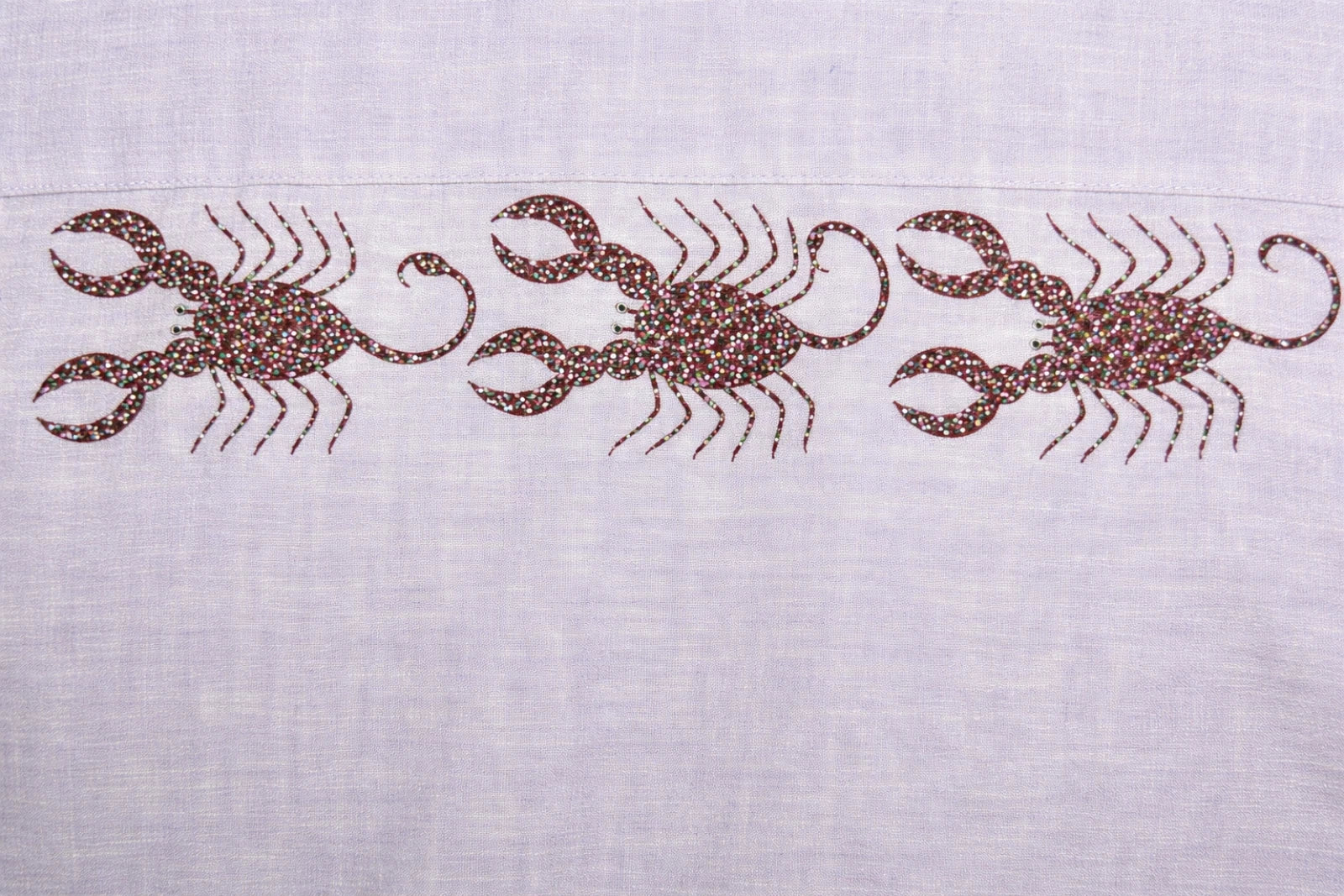 Close-up of three hand-painted Bhil scorpion artworks across back shoulder panel on linen shirt showing detailed dot work.