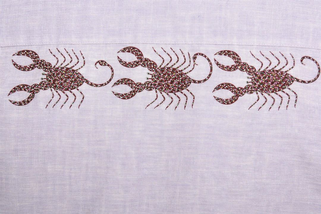 Close-up of three hand-painted Bhil scorpion artworks across back shoulder panel on linen shirt showing detailed dot work.