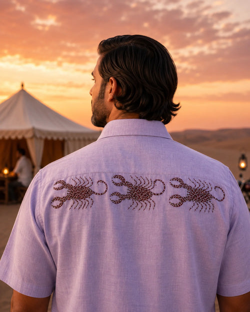 Hand-painted Bhil linen shirt featuring three scorpion artworks across the back yoke, photographed in a desert camp setting at dusk.