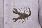 Close-up of hand-painted Bhil scorpion artwork on linen shirt pocket showing intricate dot work.