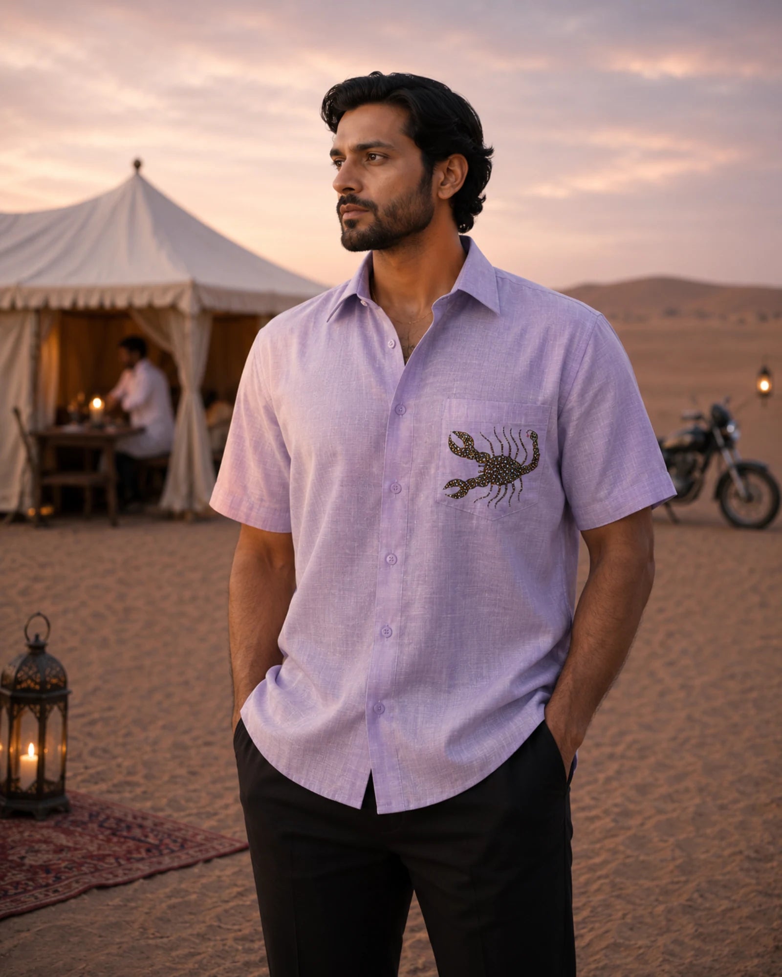 Hand-painted Bhil linen shirt featuring a scorpion artwork on the pocket, photographed in a desert camp setting at dusk.