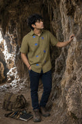 Bhil Snail-ed It hand-painted linen shirt featuring seven hand-painted snail artwork across the front, photographed during cave exploration among limestone formations in natural light.