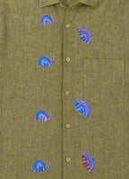 Bhil hand-painted linen shirt featuring seven snail artworks arranged across the front panel, photographed at the entrance of a limestone cave during an early morning exploration.