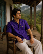 Bhil hand-painted linen shirt featuring scattered Mahua blossom motifs across the front, observed while seated in the verandah of a vintage farmhouse overlooking mist-covered valley landscapes and surrounding greenery.