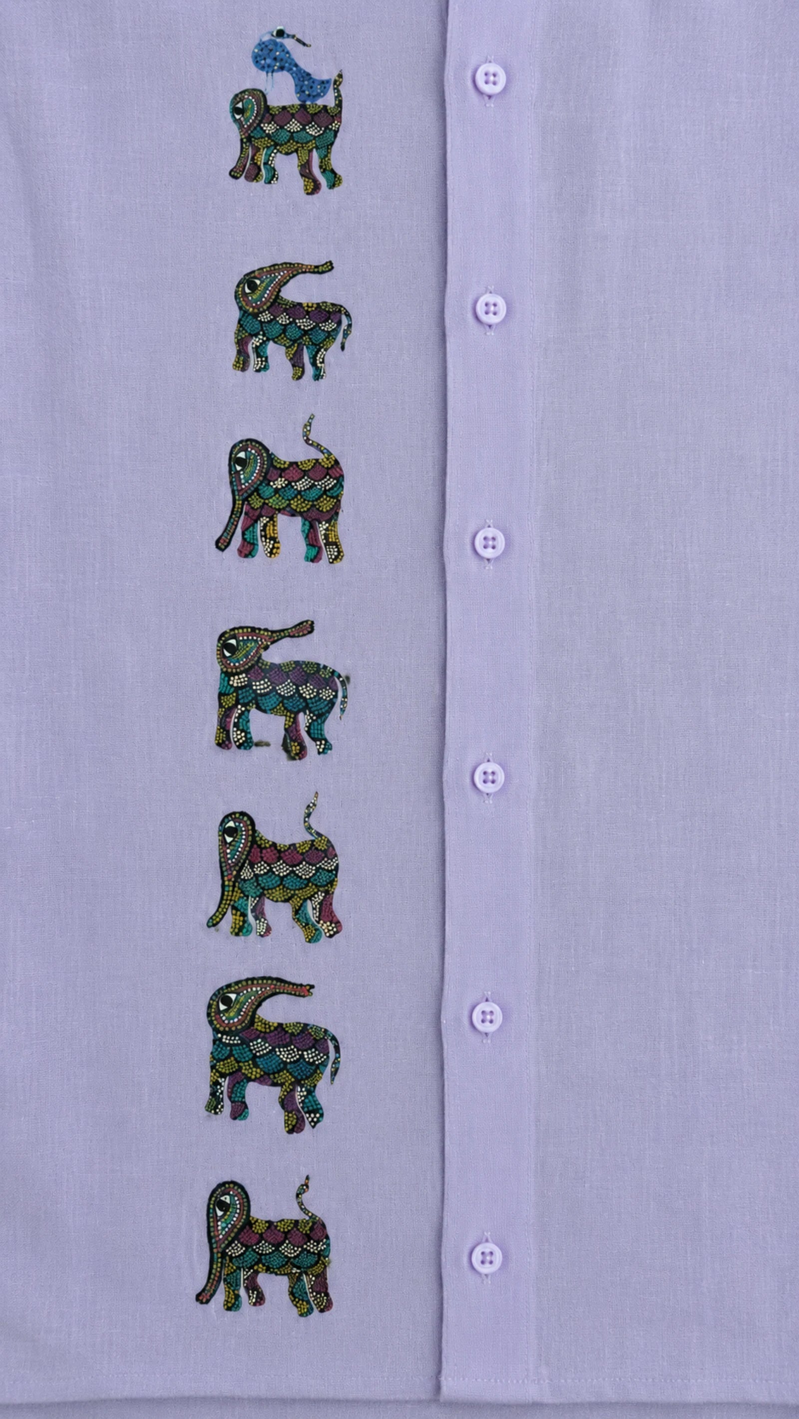Close-up of the front panel of a hand-painted linen shirt featuring seven elephant motifs arranged vertically, with a blue bird perched on the uppermost elephant, showcasing detailed Bhil-inspired brushwork and painted surface details.