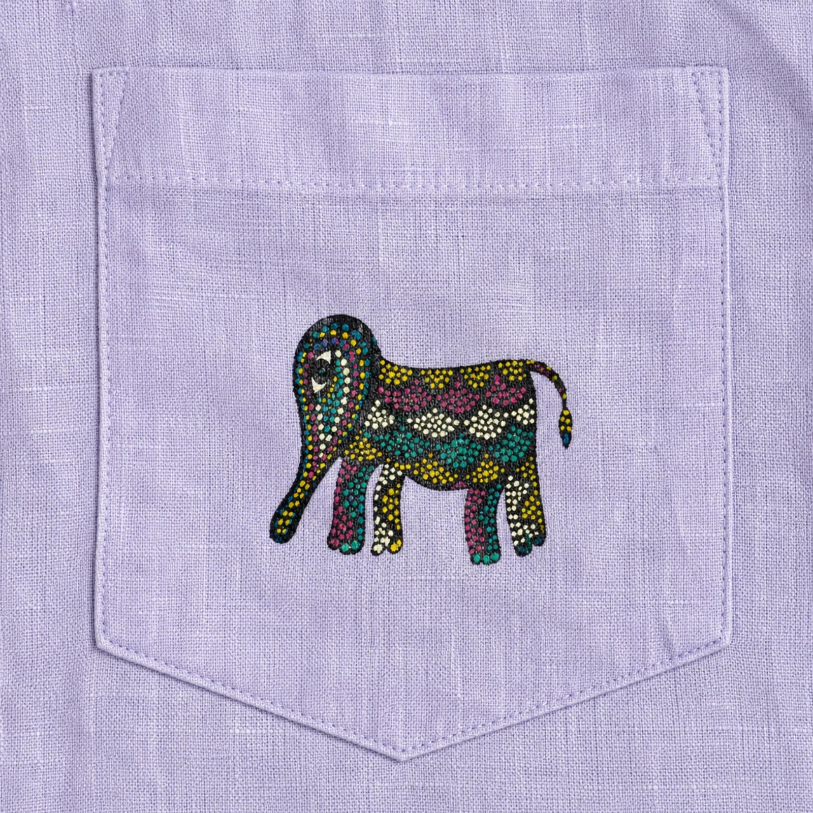 Close-up of front pocket showing a hand-painted Bhil elephant on a linen shirt, revealing intricate dot work, pigment variation, and visible textile weave.