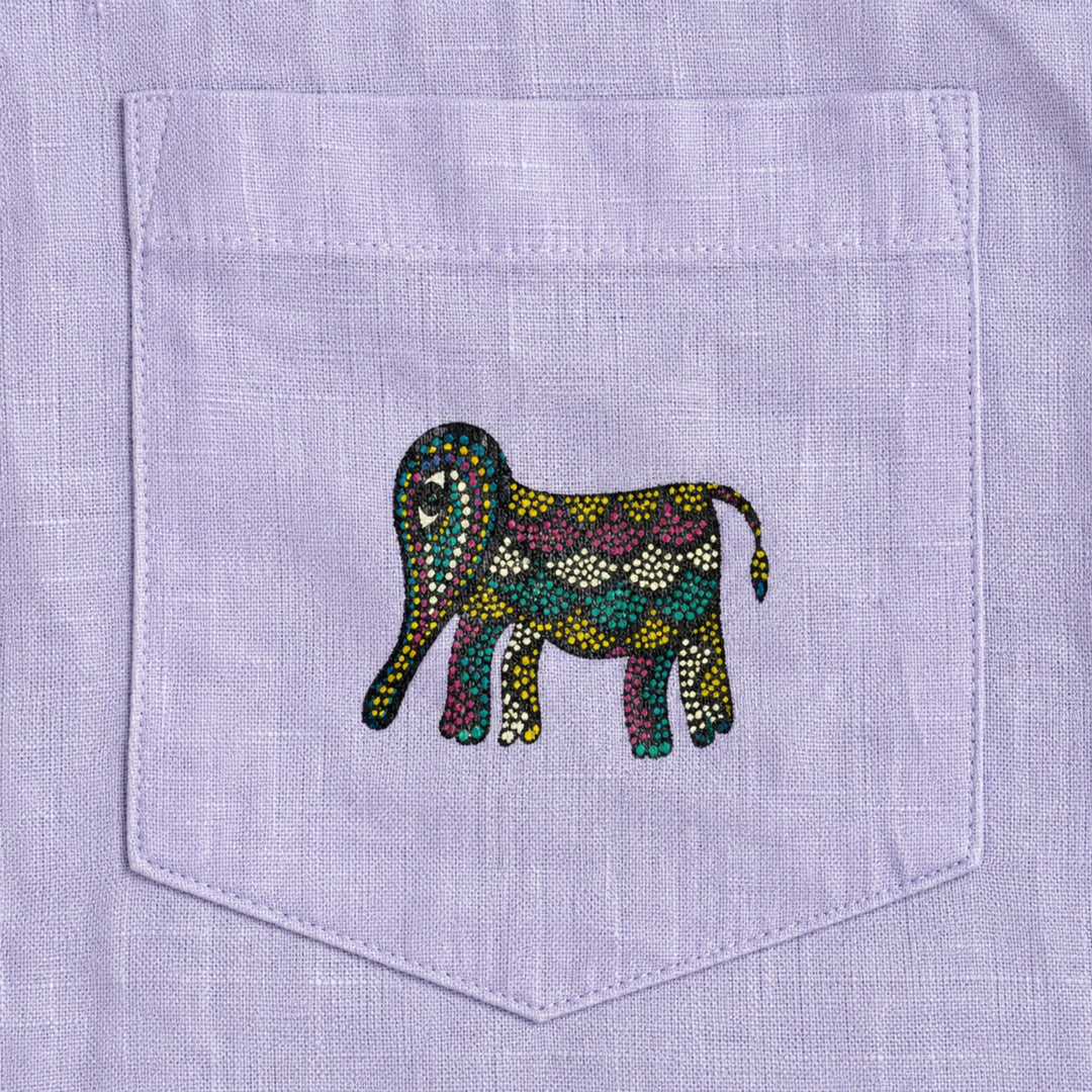 Close-up of front pocket showing a hand-painted Bhil elephant on a linen shirt, revealing intricate dot work, pigment variation, and visible textile weave.