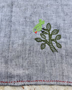 Close-up of a bird perched on a leafy tree artwork on a Bihar Sujani hand-embroidered khadi handkerchief.