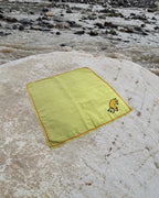 Hand-embroidered Bihar Sujani khadi handkerchief featuring a pet animal artwork, photographed on a weathered river stone.