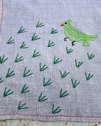 Close-up of the green parrot artwork on a hand-embroidered Bihar Sujani khadi cotton handkerchief.
