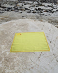 Hand-embroidered Bihar Sujani khadi handkerchief featuring a Yin Yang fish artwork, photographed on a weathered river stone.