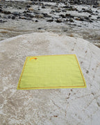 Hand-embroidered Bihar Sujani khadi handkerchief featuring a Yin Yang fish artwork, photographed on a weathered river stone.