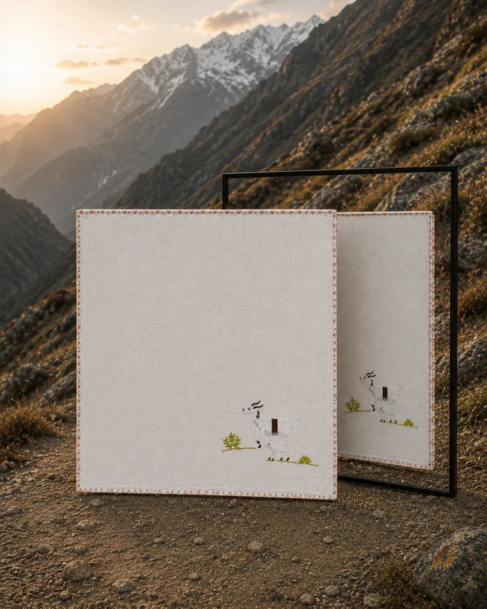 Chamba Rumal - Himalayan Goat in handwoven khadi cotton, featuring a hand-embroidered Himalayan goat and kid, shown against a steep mountain landscape with a mirror revealing identical do-rukha embroidery on both sides.