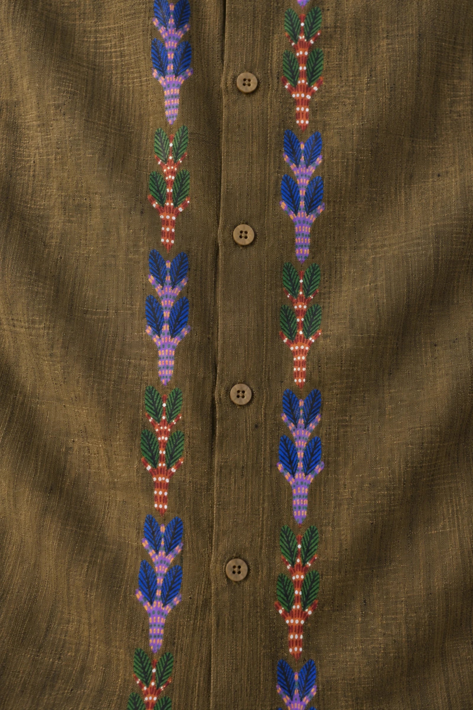 Gond hand-painted linen shirt featuring vertically extending botanical motifs constructed through layered linear dash detailing and rhythmic pigment strokes beside a structured button placket on an olive linen surface with visible weave texture, natural slub variation, and handcrafted artisanal character.