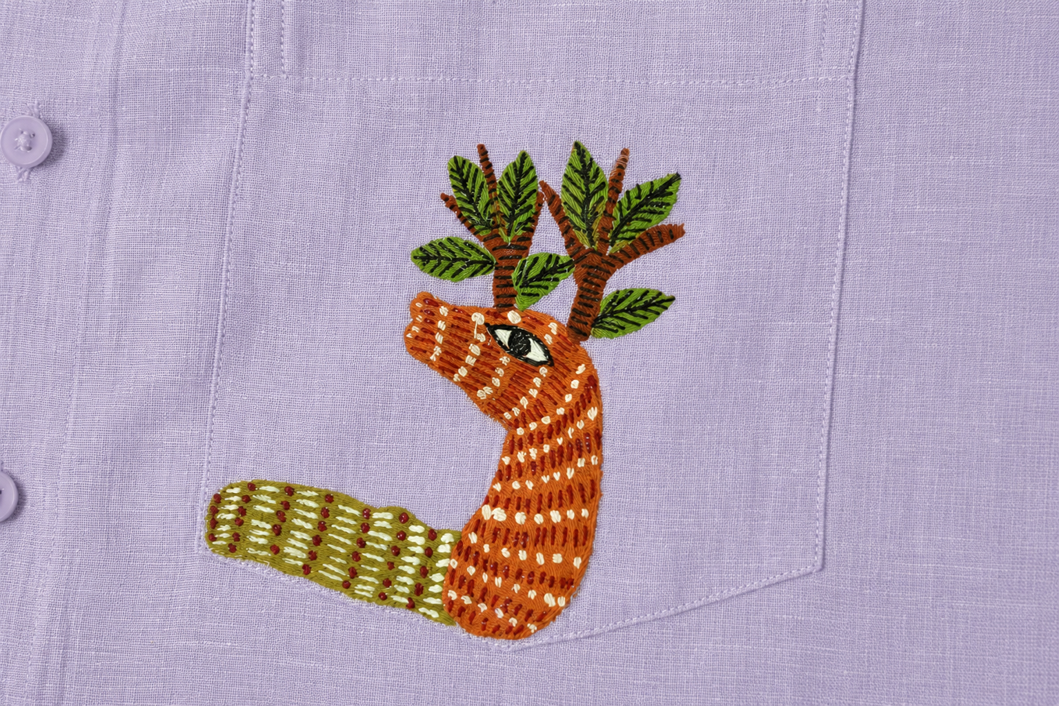 Gond hand-painted linen shirt pocket close-up featuring a hand-painted deer form with branching tree structures emerging from the head, constructed through layered linear surface detailing and patterned mark-making on a structured chest pocket.