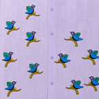 Close-up of Gond hand-painted linen shirt featuring scattered bird motifs perched on branching forms across the front panel, showing fine line work, balanced spacing, and hand-painted surface detail.