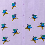 Load image into Gallery viewer, Close-up of Gond hand-painted linen shirt featuring scattered bird motifs perched on branching forms across the front panel, showing fine line work, balanced spacing, and hand-painted surface detail.