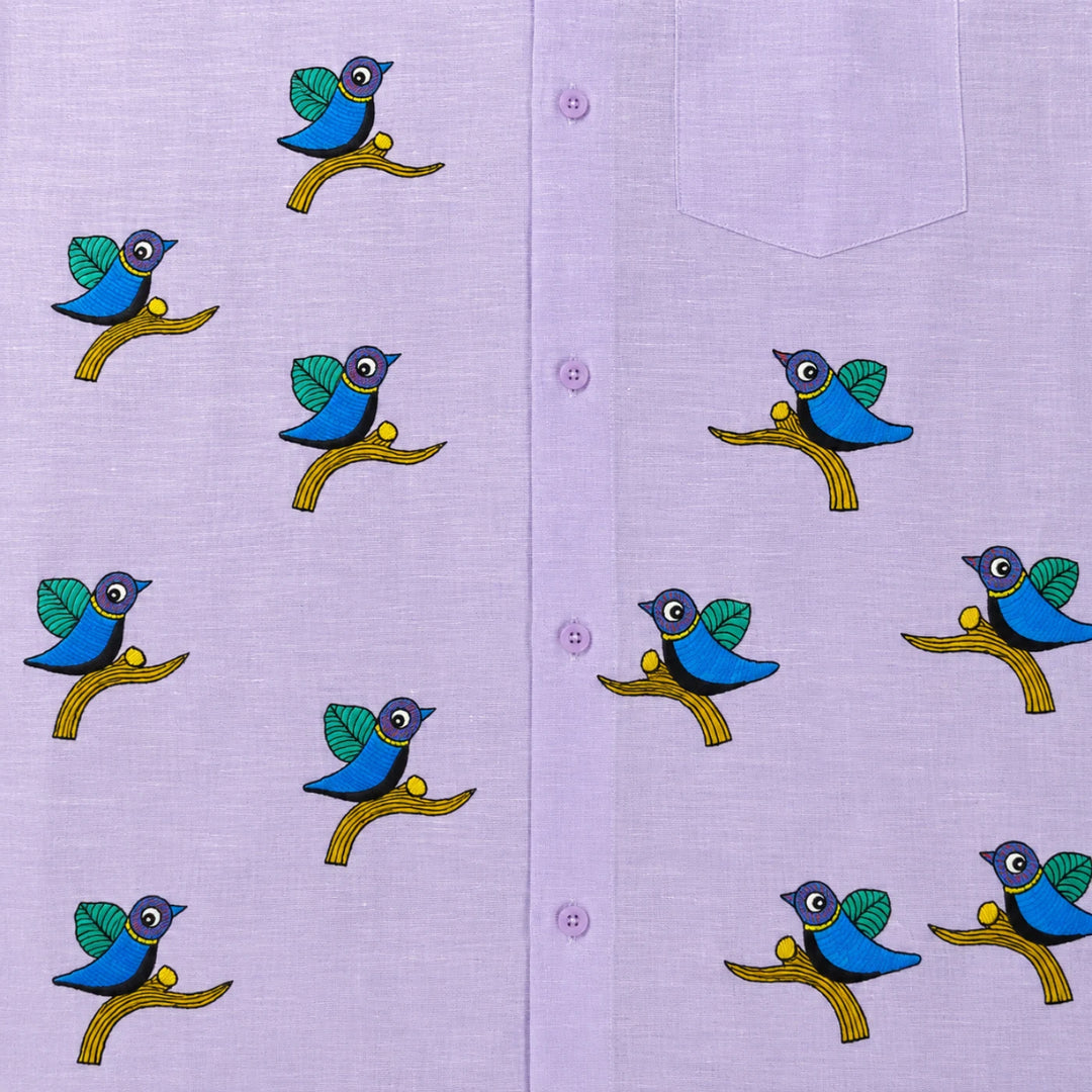 Close-up of Gond hand-painted linen shirt featuring scattered bird motifs perched on branching forms across the front panel, showing fine line work, balanced spacing, and hand-painted surface detail.