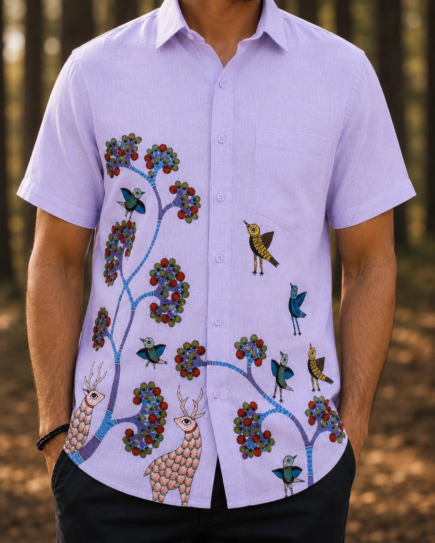 Close-up of Gond hand-painted linen shirt featuring birds perched across branching tree forms with deer motifs along the lower front panel, showing intricate line-based Gond strokes, hand-painted surface detail, and natural linen texture.
