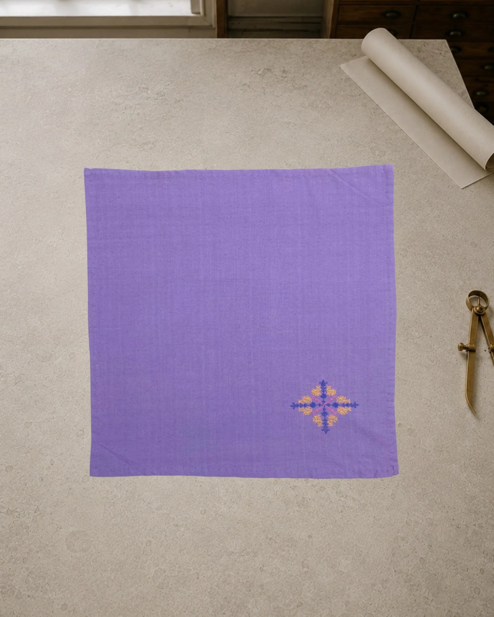 Kasuti Agumbe hand-embroidered khadi cotton handkerchief featuring a peacock motif in Murgi and Gavanti stitches, displayed on a pale stone conservation table.