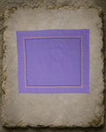 Kasuti Kodachadri hand-embroidered khadi cotton handkerchief laid open on an aged stone slab, framed by a continuous Betel Box border in deep blue and warm orange thread.