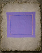 Kasuti Kodachadri hand-embroidered khadi cotton handkerchief laid open on an aged stone slab, framed by a continuous Betel Box border in deep blue and warm orange thread.