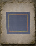 Kasuti Kudremukh hand-embroidered khadi cotton handkerchief with a continuous yellow and orange Betel Box motif border, displayed on a weathered stone surface.
