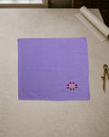 Kasuti Sahyadri hand-embroidered khadi cotton handkerchief featuring a peacock motif in Murgi and Gavanti stitches, displayed on a pale stone conservation table.