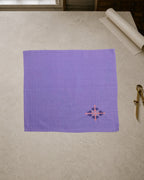 Kasuti Sahyadri hand-embroidered khadi cotton handkerchief featuring a peacock motif in Murgi and Gavanti stitches, displayed on a pale stone conservation table.