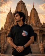 Odisha Pattachitra hand-painted linen shirt featuring a portrait motif on the chest pocket, observed before temple architecture in warm evening light.