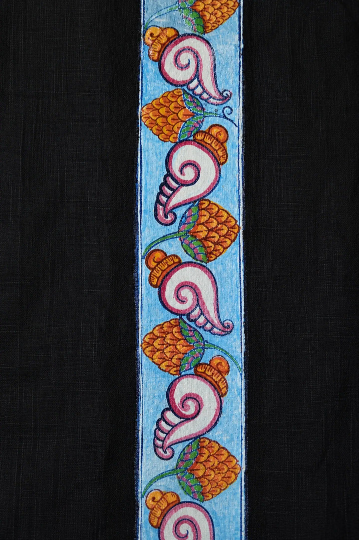 Close-up of hand-painted Odisha Pattachitra detailing running vertically along the placket of a linen shirt, showing repeating conch forms, floral elements, and fine painted linework.