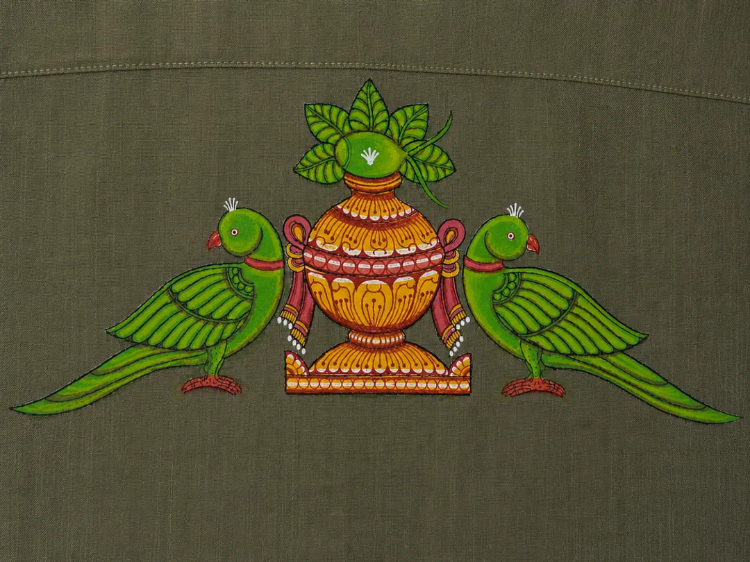 Close-up of hand-painted Odisha Pattachitra back motif on linen shirt, showing twin parrot forms, ceremonial kalash detailing, pigment variation, and textile weave.