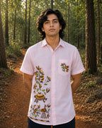 Sohrai Aikya hand-painted linen shirt in a natural woodland setting, showing the right front composition and bird artwork on the chest pocket.