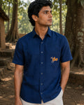 Sohrai Jeev Dhara hand-painted linen shirt in a forest setting, featuring a solitary peahen painted on the chest pocket.