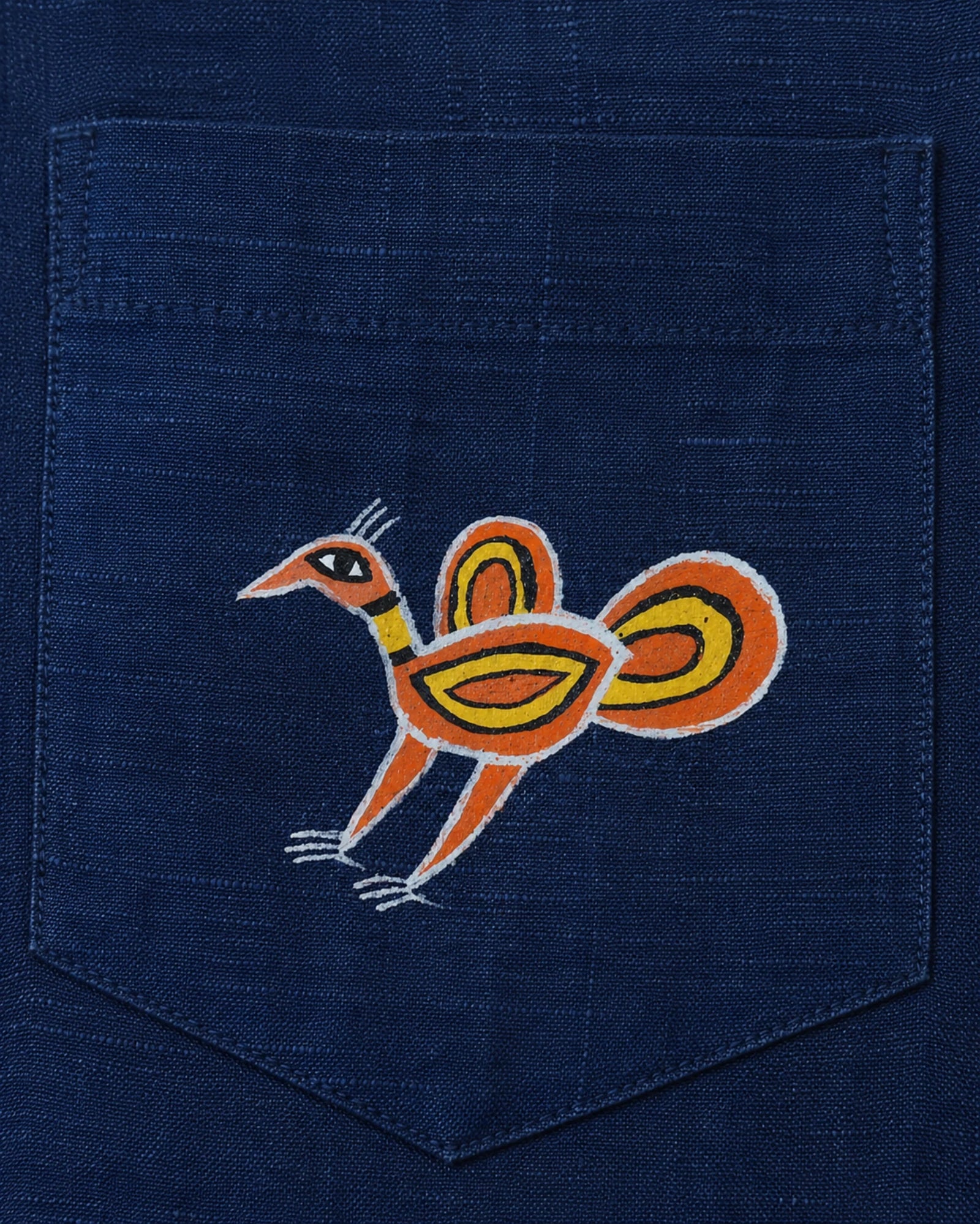 Close-up of the Sohrai Jeev Dhara linen shirt pocket featuring a solitary hand-painted peahen.
