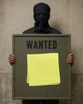 Masked figure holding a weathered “WANTED” sign displaying a folded, hand-hemmed Citron khadi handkerchief.