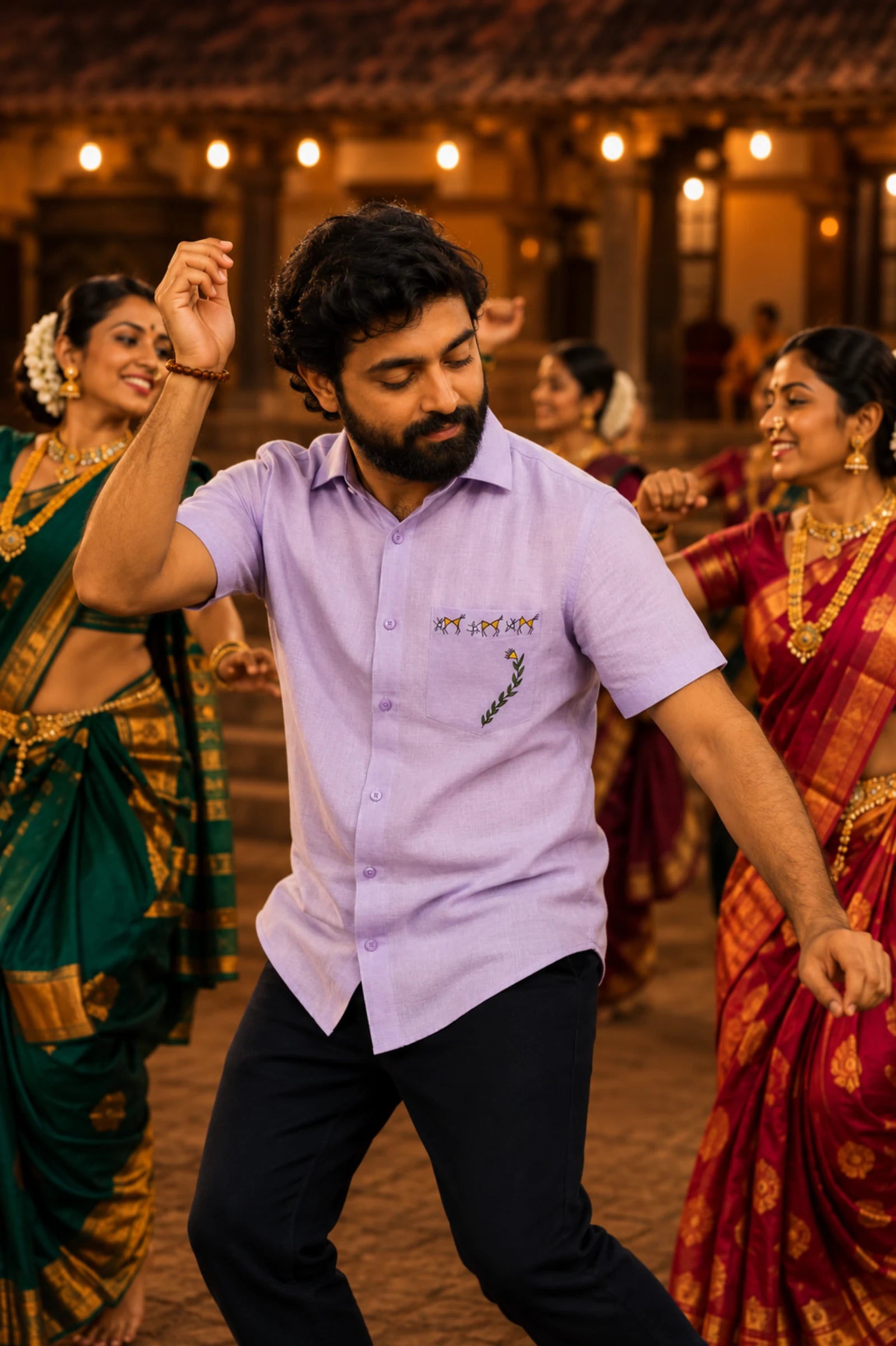 Warli Aabha hand-painted linen shirt featuring hand-painted goats, celebratory figures and a flowering vine artwork on the chest pocket, observed during a traditional Lavani dance gathering in a heritage Maharashtrian courtyard illuminated by warm evening light.
