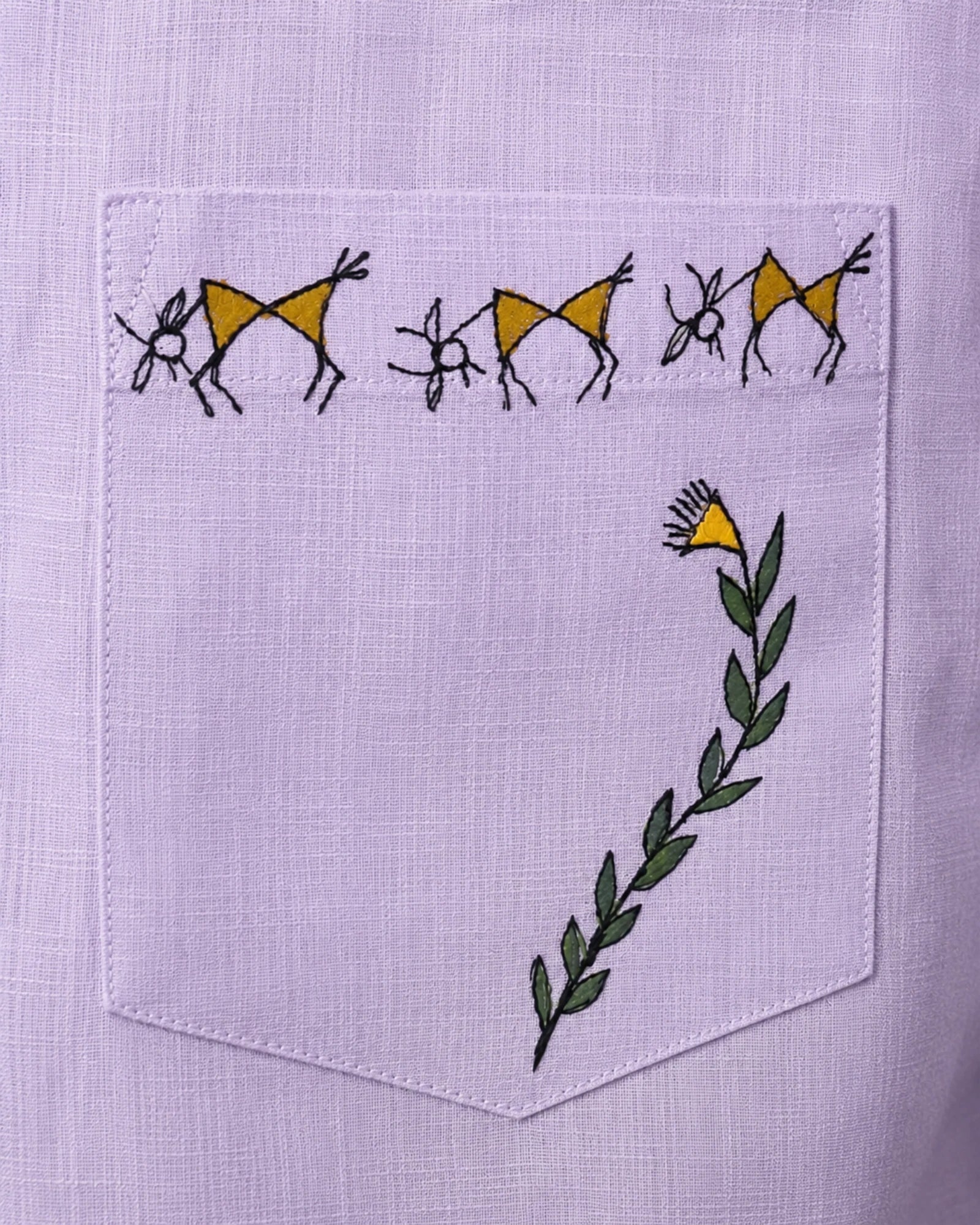 Close-up of the chest pocket artwork on the Warli Aabha hand-painted linen shirt, featuring three goats separated by floral motifs along the pocket opening and a flowering vine rising diagonally across the pocket corner in a hand-painted Warli composition.