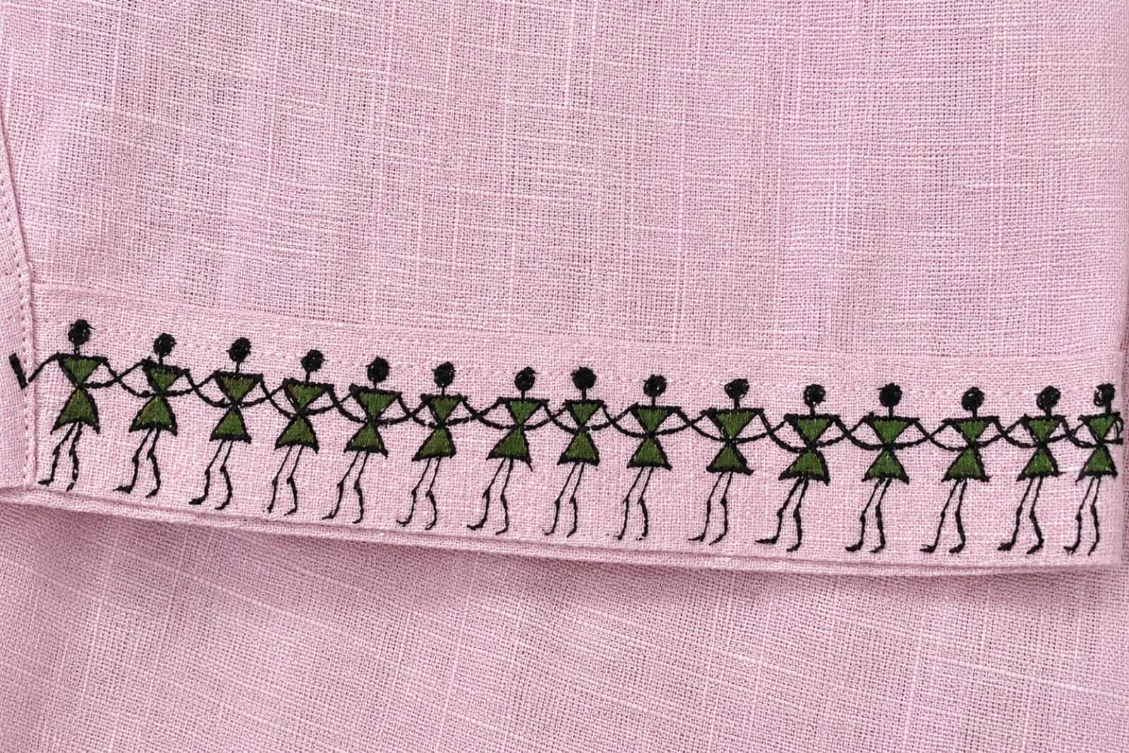 Warli hand-painted linen shirt sleeves border close-up featuring a continuous Warli tarpa dance painted along the sleeve hem.