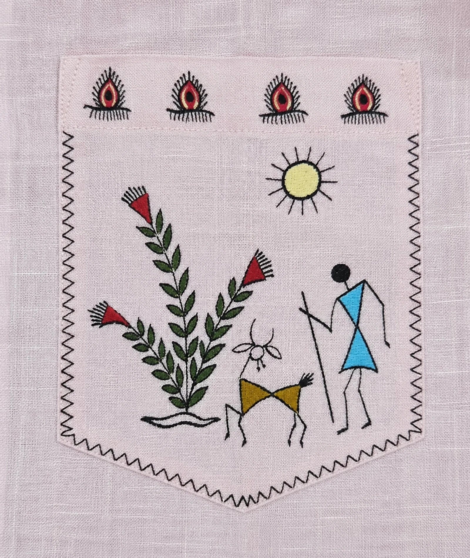 Warli Pravah chest pocket artwork depicting a flowering plant, animal and human figure beneath the sun, hand-painted on pure linen within a decorative warli border.