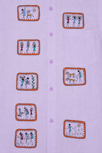 Warli Samriddhi hand-painted linen shirt front panel close-up showing eight framed Warli artworks arranged across the front, with five artworks along the right placket and three along the left, depicting village life, celebration, farming, and daily activities.