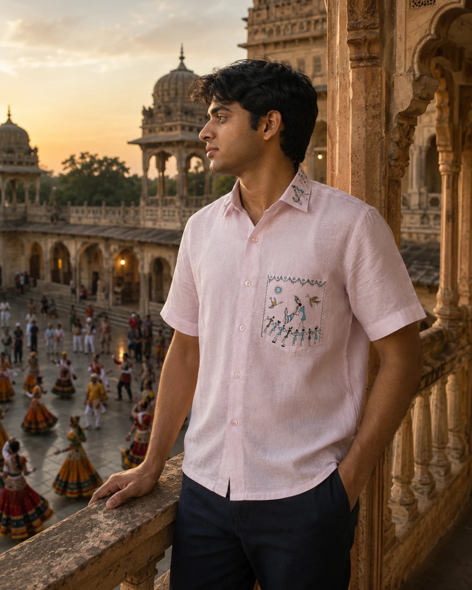 Warli Ullas hand-painted linen shirt featuring a Tarpa dance artwork unfolding across the pocket and collar, where dancers, birds and ceremonial artworks surround a tarpa-led celebration, worn while overlooking a traditional dance gathering from a heritage palace terrace in warm evening light.