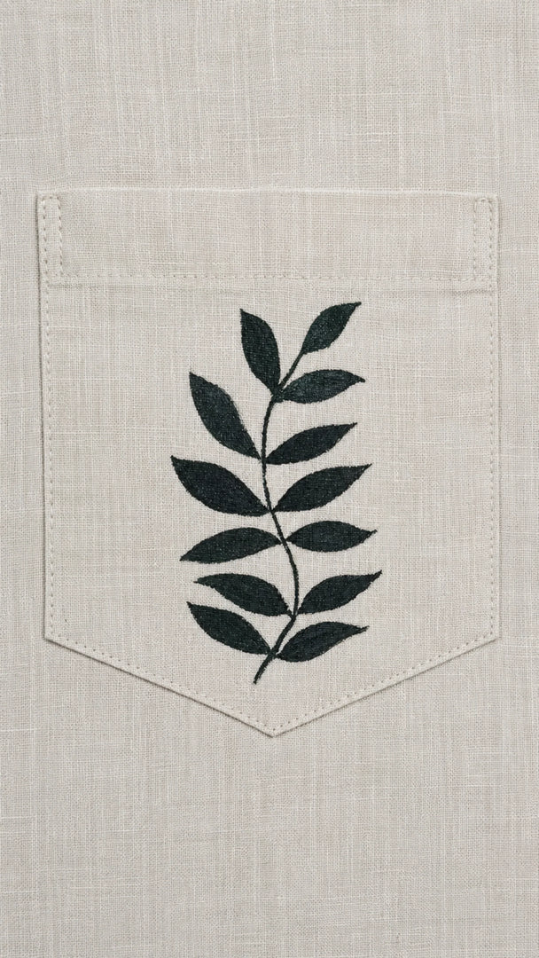 Botanical artwork detail above the pocket of the Padchinh hand-painted linen shirt, revealing the brushwork and fine line detailing of the original artwork.