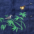 Bottom right artwork detail from the Vanantara hand-painted linen shirt featuring a bird perched across branching bamboo forms with a butterfly above, showcasing the brushwork, composition and fine detailing of the original artwork.