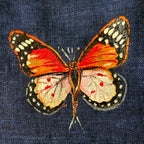 Upper chest butterfly detail from the Vanantara hand-painted linen shirt, featuring an open-wing butterfly with visible brushwork, wing pattern detailing and fine line work.
