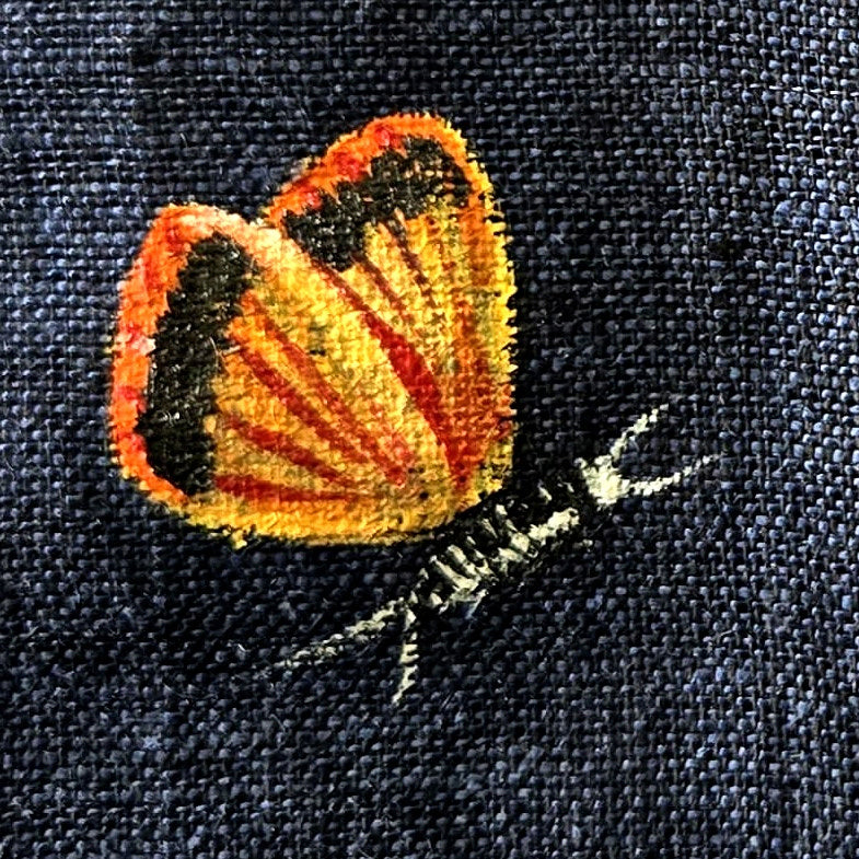 Mid chest butterfly detail from the Vanantara hand-painted linen shirt, featuring a partially folded butterfly with visible brushwork, wing pattern detailing and fine line work.
