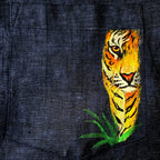 Pocket artwork detail from the Vanantara hand-painted linen shirt, featuring a tiger emerging through tall grass and revealing the brushwork, colour layering and fine line detailing of the original artwork.
