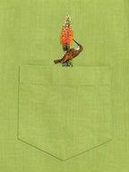 Woodpecker perched on a botanical branch above the pocket of the Vanchar hand-painted linen shirt.